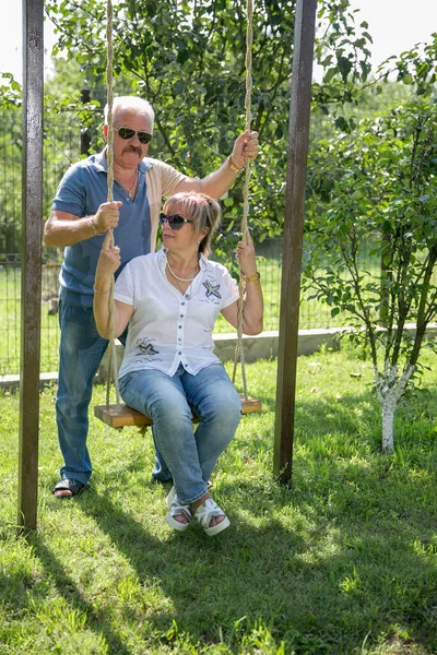 Orta yaşlı yaşlı çift salıncakta sallanıyor. Olgun yaşam tarzı ve aşk konseptiyle birlikte.