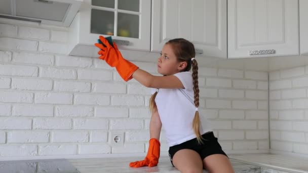 Een klein meisje veegt de keuken af. Taken voor kinderen — Stockvideo