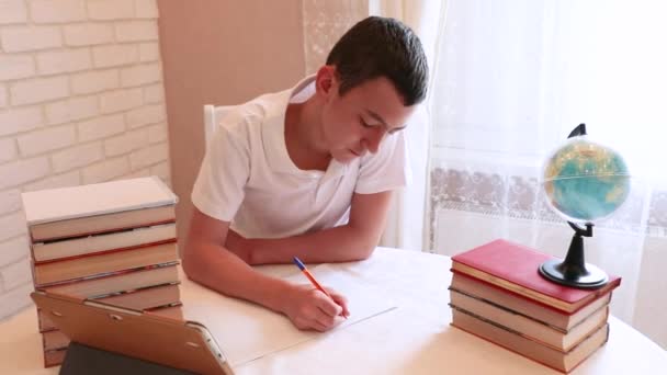 Ένα σχολιαρόπαιδο κάνει τα μαθήματά του. Βιβλία και σημειωματάρια στο τραπέζι — Αρχείο Βίντεο
