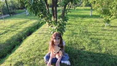 Küçük oyuncak ayısına açık havada kitap okuyan bir kız. Küçük kız oyuncaklarıyla yeşil çimlerde oynuyor.