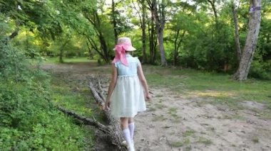 Sevimli küçük kız devrilmiş ağacın gövdesinde yürüyor.