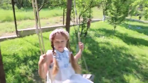 女の子が揺れる スイングで揺れる緑の庭のかわいい女の子 — ストック動画