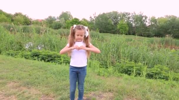 Una Niña Sonríe Muestra Una Señal Corazón Con Las Manos — Vídeos de Stock