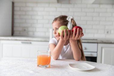 Mutfakta meyve suyu ve elma suyu olan küçük bir kız. Sağlıklı yemek. Vejetaryenlik. Çocuk bitki yiyeceği yiyor. vitaminler