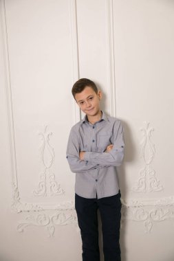 Beyaz duvara karşı duran yakışıklı bir çocuğun portresi.