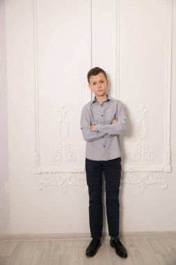 Beyaz duvara karşı duran yakışıklı bir çocuğun portresi.