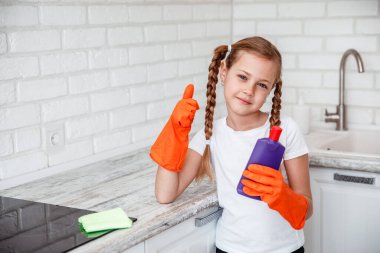 Temizlik. Küçük kız güzel mutfakta mutfak sobasını temizliyor.