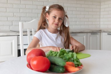 Mutfakta sebze doğrayan küçük bir kız. vejetaryenlik
