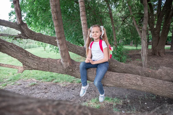 Liten Flicka Med Ryggsäck Sitter Ett Träd Skogen Parken Barn — Stockfoto