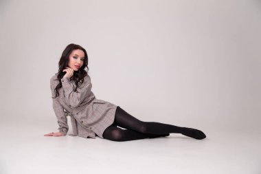 Güzel seksi kız öğrenci gri ya da beyaz arka planda yatıyor.