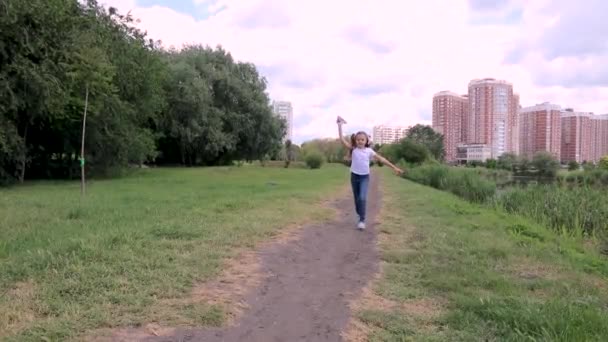 Niño corre con un avión de papel. chica en un parque verde, bosque — Vídeos de Stock