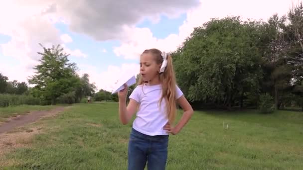 Het kind lanceert een papieren vliegtuig. meisje in een groen park — Stockvideo