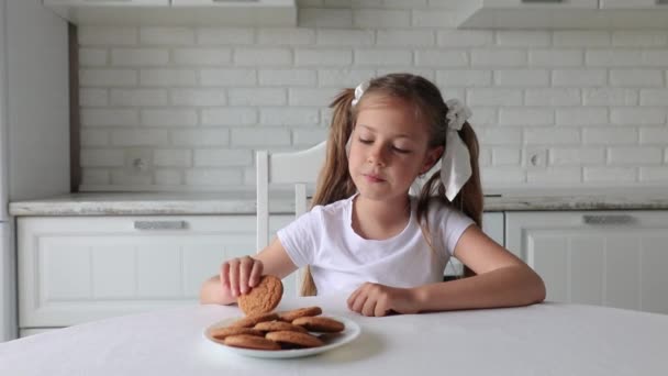 Belle petite fille mange des biscuits. le bébé prend son petit déjeuner dans la cuisine. — Video