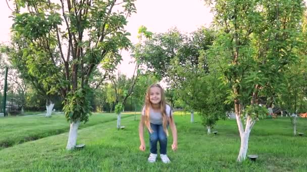 Маленька Дівчинка Довгим Волоссям Джинсах Стрибає Маленька Дівчинка Зеленому Саду — стокове відео