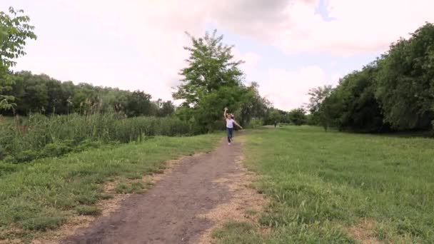 아이는 종이비행기를 타고 달립니다. 숲 속의 푸른 공원에 있는 소녀 — 비디오