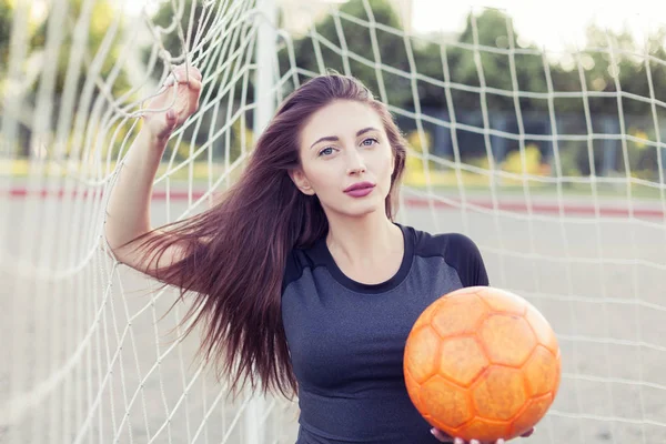 サッカー ゴールの隅に立っている彼女の手にボールを持つ若い女性 — ストック写真