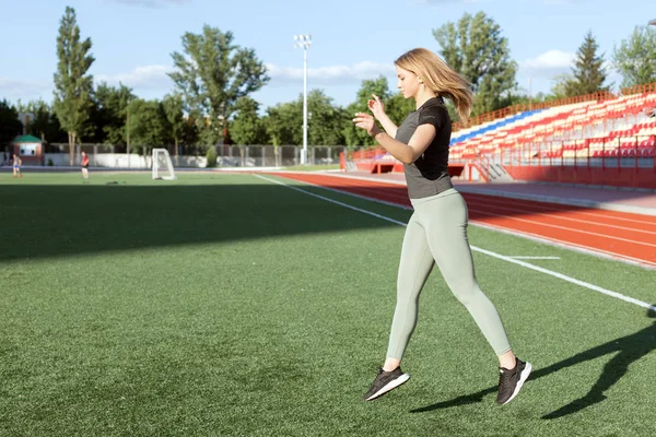 Genç kız stadyum üzerinde atlama yapmaktadır.
