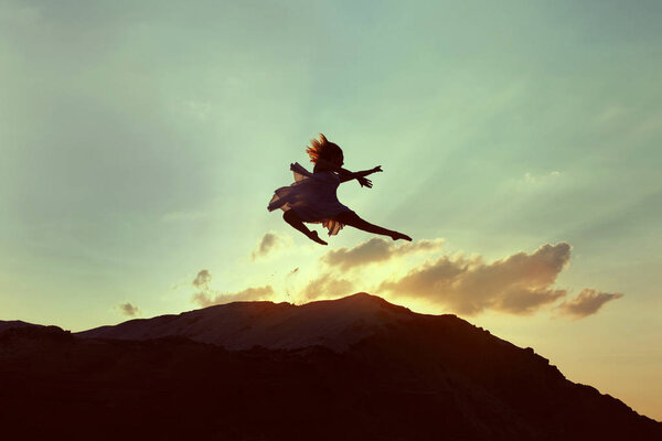 Silhouette of a dancer jumping in the setting sun in the desert.