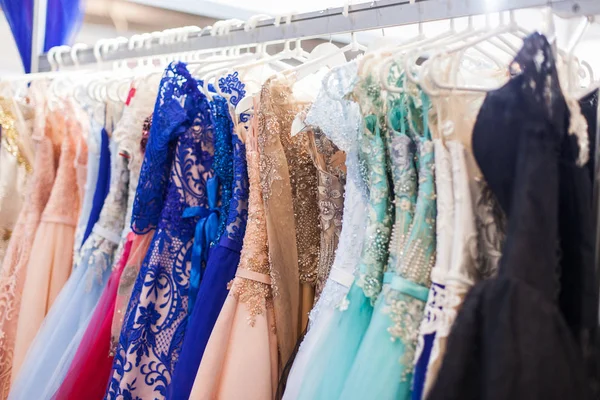 Many chic evening dresses hanging on a rack in the shop.