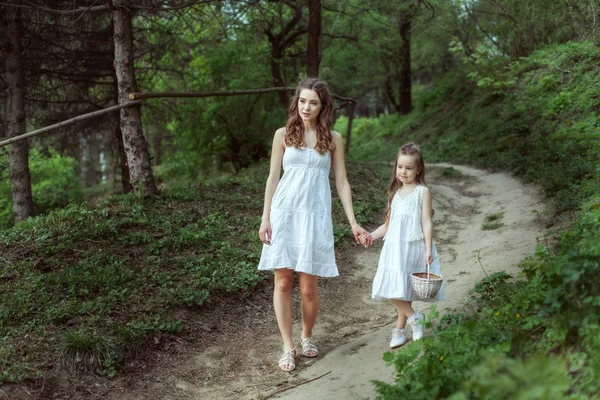 年轻的母亲与她的女儿去在树林里的小径 — 图库照片