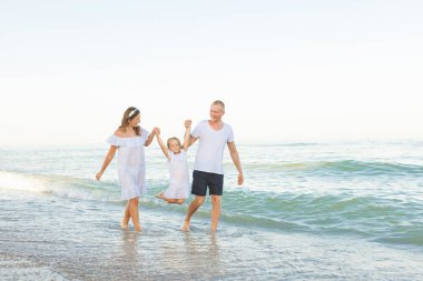 Genç Anne deniz kıyısı yürü ve el ile kızları götür.