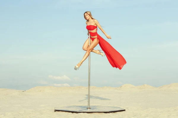 Çölde bir pilon üzerinde yapan kırmızı elbiseli Genç kadın.