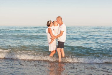 Anne kızı olan deniz kıyısı ve kucaklama üzerinde durun. Kız babası öpüşme.