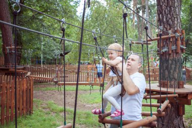 Babası kızını ip parkta bir engeli aşmak yardımcı.