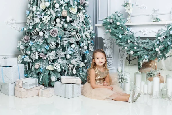 部屋でクリスマス ツリーのそばに座っている少女 — ストック写真