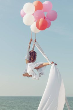 Genç kadın üzerinde tuvalleri stunts yapıyor. Balonlar tuvaller havada tutun..