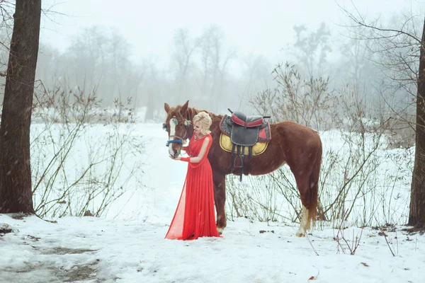 Kobieta Czerwonej Sukience Zimowym Lesie Ona Głaszcze Konia — Zdjęcie stockowe
