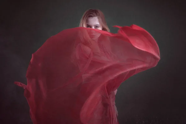 Mujer con un vestido rojo en una habitación oscura entre la harina . — Foto de Stock