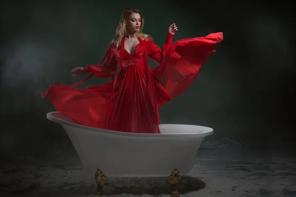 Mulher em um vestido vermelho está de pé no banho . — Fotografia de Stock