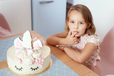 Güzel bebek kız bir parmak ile bir Doğum günü pastası tadı.
