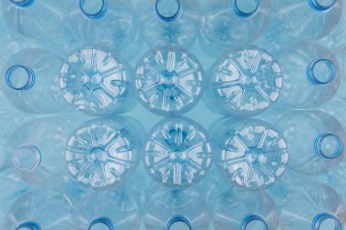 Mavi arka planda üst üste istiflenmiş boş, şeffaf plastik şişeleri gösteren yatay renk görüntüsü. Geri dönüşüm ve çevre kavramı.