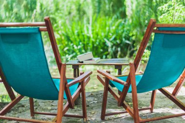 Bahçede ahşap plaj sandalyeleri ve bahçede birkaç kitap olan yatay renk görüntüsü. Rahatlatıcı yer kavramı.