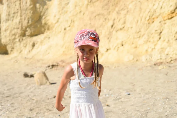 angry little six year old kid girl in a cap in nature in the desert