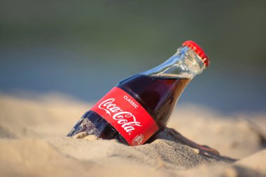 Gomel, Belarus - 2 Eylül 2020: Coca Cola, Fanta, Sprite, Schwepps in cans and bottle, arka planda bir yaz plajında meşrubat.