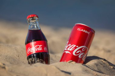 Gomel, Belarus - 2 Eylül 2020: Coca Cola, Fanta, Sprite, Schwepps in cans and bottle, arka planda bir yaz plajında meşrubat.