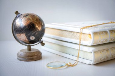 Beyaz kitaplık ve kitap standında küçük bir küre ve çeşitli küçük şeyler..