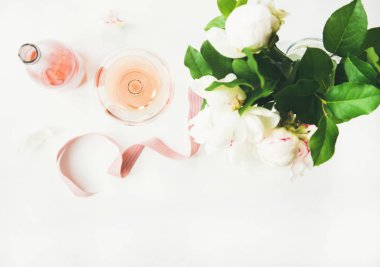 Gül cam ve şişe şarap pembe dekoratif kurdele ve şakayık çiçekleri buketi beyaz masa arka plan üzerinde