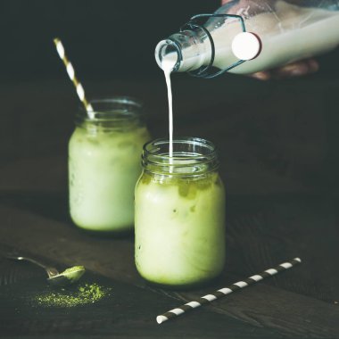 Buzlu Hindistan cevizi matcha latte içmek, ferahlatıcı soğuk el dökülen süt şişe