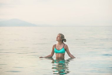 Antik kale duvarı ve Alanya şehir merkezine, Akdeniz Türkiye tersanelerinde yakınındaki plajda turkuaz mayo ayakta hala deniz sularında giyen genç güzel slavian kadın turist