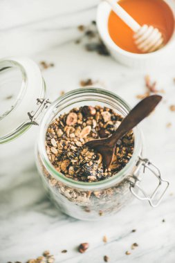 Sağlıklı kahvaltı hazırlığı. Cam açık renkli mermer üzerine fındık ile buğday ve çikolata granola