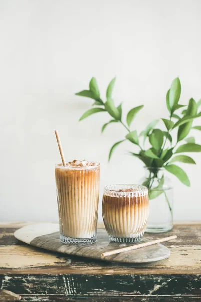 牛乳とストロー ボード上の白い壁 背景に緑の植物の枝を持つ背の高いグラスでアイス コーヒー — ストック写真