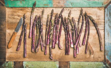 taze çiğ çiğ mor kuşkonmaz satır ve ahşap tepsi arka plan üzerinde bıçak