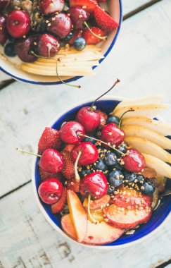 Sağlıklı kahvaltı güler yüzlü kase taze meyve ve çilek, arı polen ve bal mavi masa arka plan üzerinde