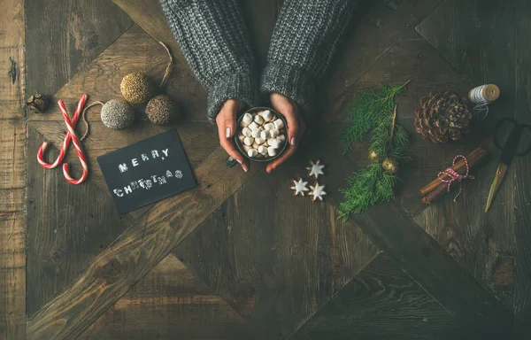 クリスマス 新年の背景 グリーティング カード きらびやかなおもちゃ ホット チョコレートのニットのセーター持株マグカップで女性の手シナモン はさみ木製のテーブルの上 — ストック写真