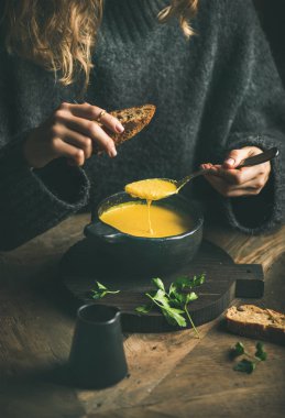 Kızarmış ekmek ile siyah kase gelen tatlı Mısır ve karides çorbası çorba yemek karanlık kış kazaklı kadın