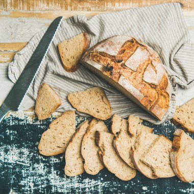 taze pişmiş hamur mayası kepekli ekmek somun yarıya ve keten peçete ve rustik masa arka plan dilimler halinde kesip